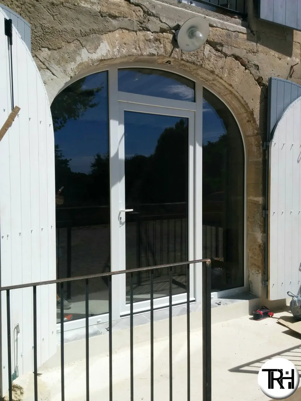 Porte-fenêtre blanche posée sous une ouverture cintrée
